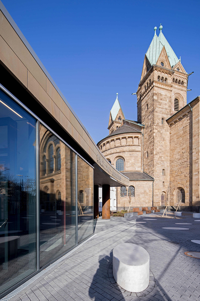 Historische Kirche mit modernem Anbau und verglastem Eingangsbereich
